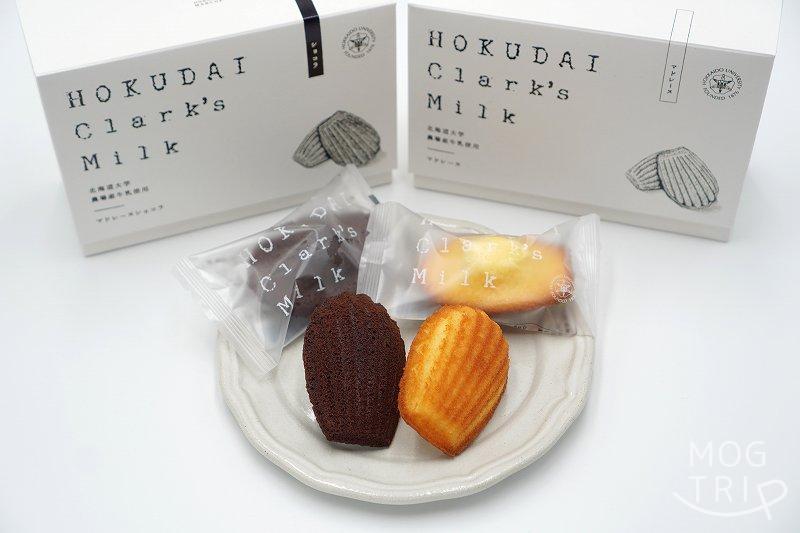 北海道大学の敷地内にある北大マルシェ の「HOKUDAI Clark's Milk マドレーヌ ショコラ」と「HOKUDAI Clark's Milk マドレーヌ」の箱がテーブルに置かれている