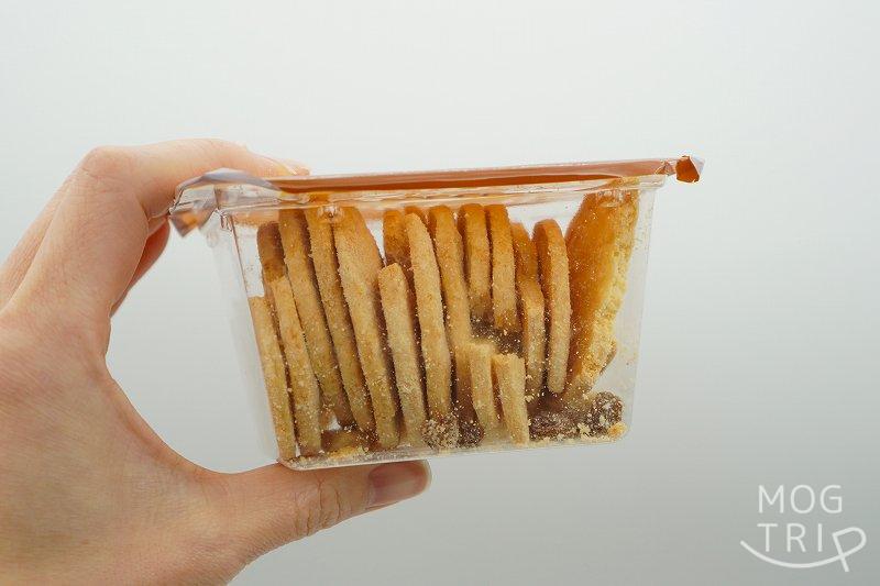 ナウオンチーズの東京駅限定品 スモーク＆カマンベールクッキーのプラスチック箱を手に持っている様子