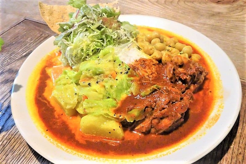 旭川「スサンタキッチン」のチキンカレーと野菜カレーの3種盛りがテーブルに置かれている