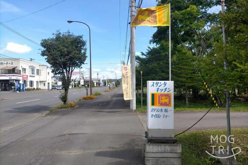 動物園通りに建つ、旭川「スサンタキッチン」の店名看板とスリランカ国旗