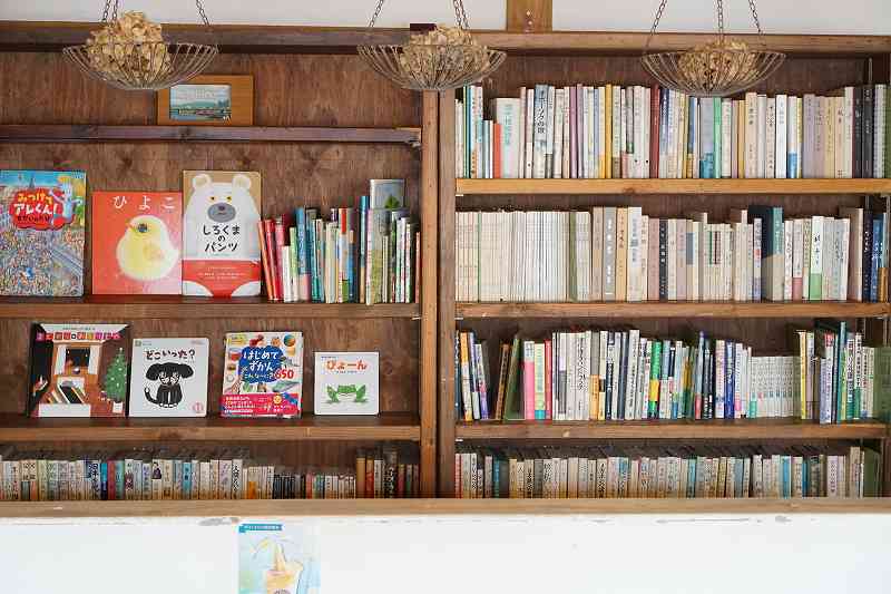 木の本棚にたくさんの本や絵本が並べられている、福吉カフェ旭橋本店の内観