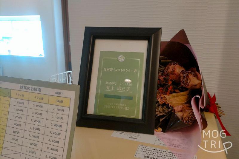 店長・井上 恵巳子さんの「日本茶インストラクター章」が棚の上に置かれている