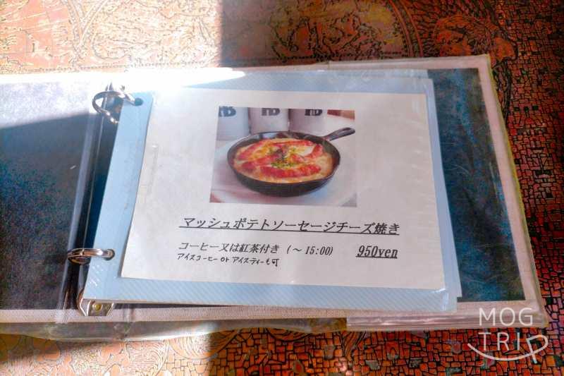 「ポテト料理専門店 穀物祭」のマッシュポテトソーセージチーズ焼きのメニュー表がテーブルに置かれている