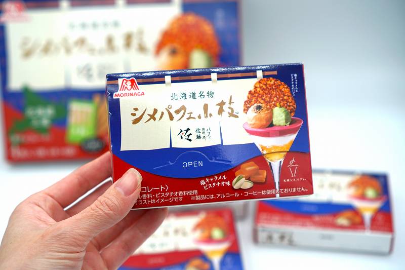 森永製菓「北海道名物 シメパフェ小枝（塩キャラメルピスタチオ味）」の小箱を手に持っている様子