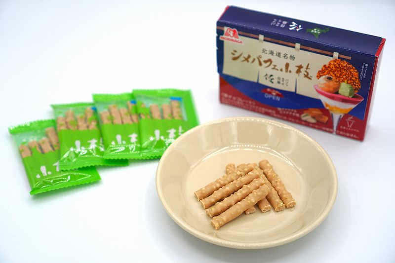森永製菓「北海道名物 シメパフェ小枝（塩キャラメルピスタチオ味）」がお皿にのせられ、テーブルに置かれている