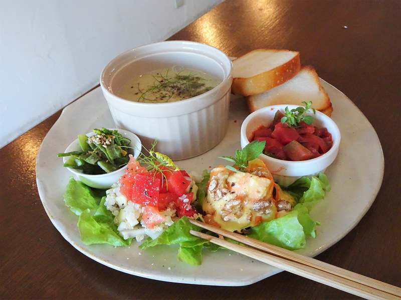 野菜のおかずとパン、スープなどがのったプレートがテーブルに置かれている