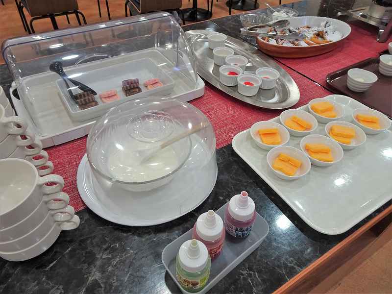 ヨーグルト、ロールケーキ、玉子焼きなどがテーブルに置かれている