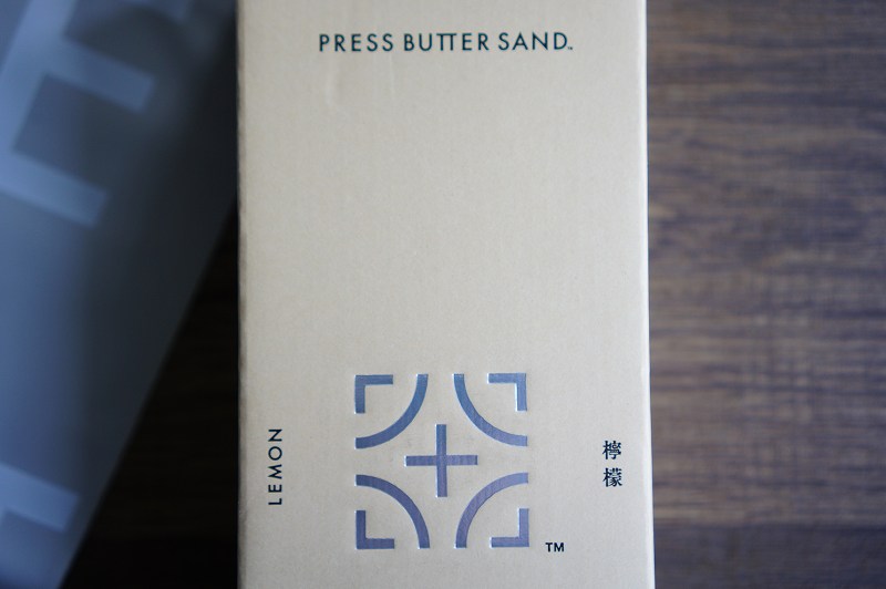 「PRESS BUTTER SAND」の文字が書かれたクリーム色の箱がテーブルに置かれている