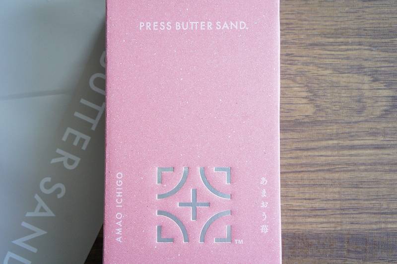 「PRESS BUTTER SAND」の文字が書かれたピンク色の箱がテーブルに置かれている