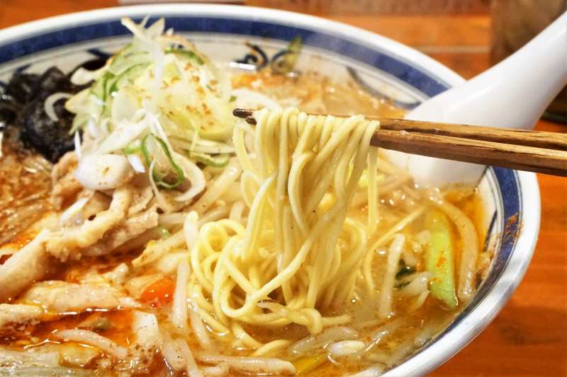 「薬膳香辛（シャンカラ）味噌 中辛」の麺を箸で持ち上げている様子