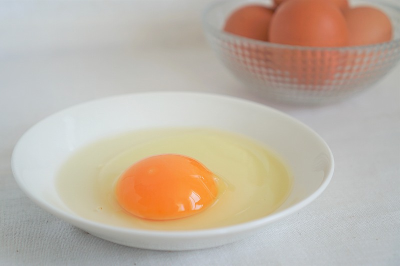 皿に割られた卵がテーブルに置かれている
