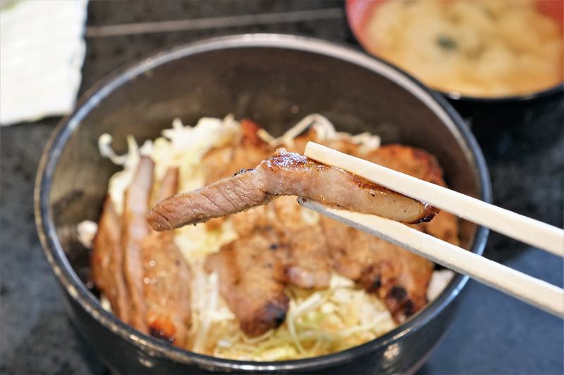 札幌味噌豚丼 きんちゃんの豚丼の豚肉を箸で持ちあげている様子
