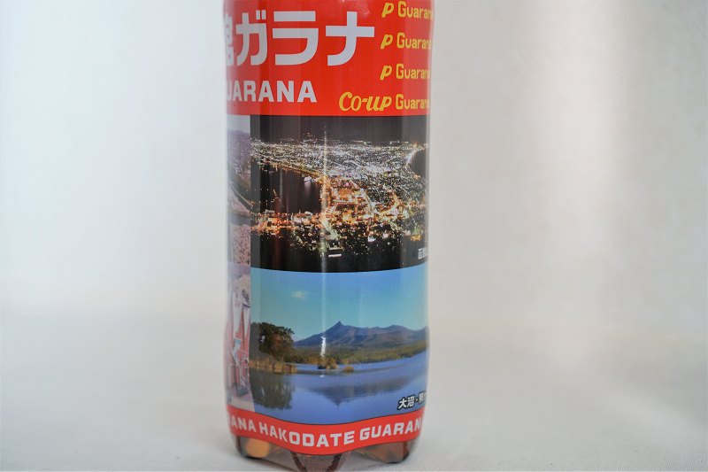 「函館山からの夜景」「大沼」の写真がプリントされたコアップガラナが、テーブルに置かれている