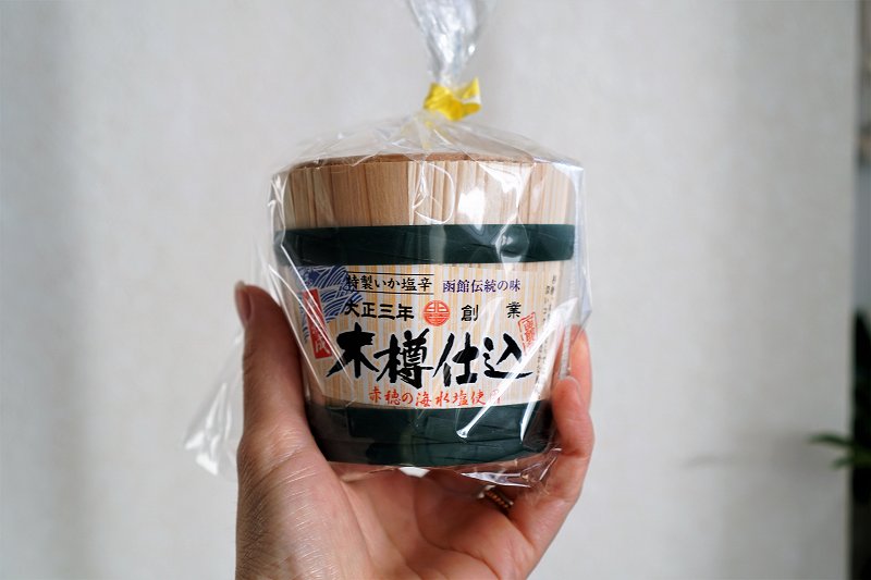 小田島水産の木樽仕込みイカ塩辛を手に持っている様子