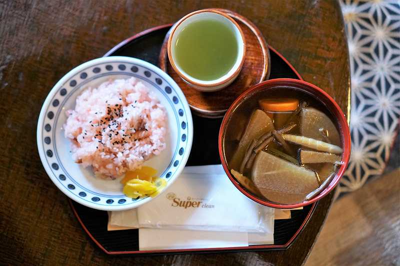 「茶房 菊泉」の、くじら汁と赤飯のセット（煎茶付き）がテーブルに置かれている