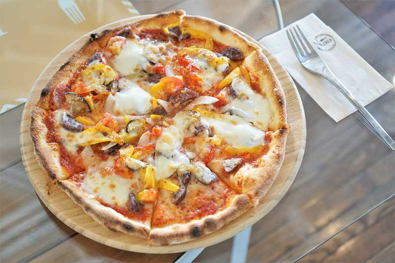 野菜やエゾシカソーセージがたっぷりのったピザがテーブルに置かれている