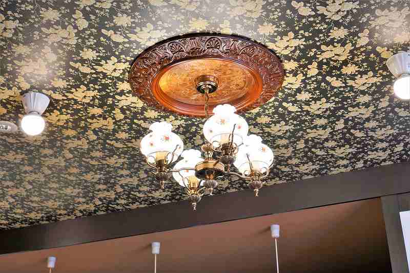シャンデリアの吊元には天井中心飾の装飾がほどこされた、喫茶ここの内観