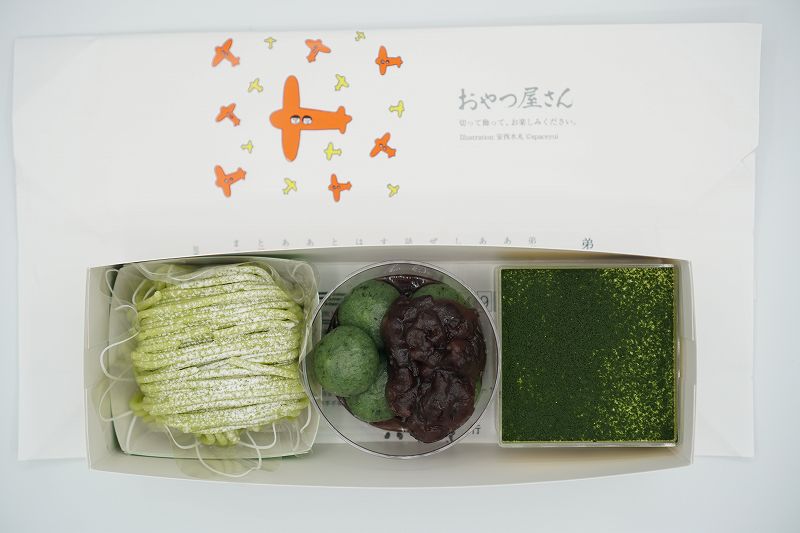 グリーンの和洋菓子が箱に入れられ、テーブルに置かれている