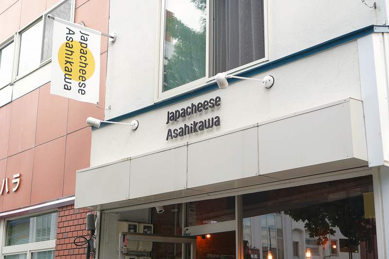 黄色の日の丸をかかげた「Japacheese Asahikawa（ジャパチーズアサヒカワ）」の店舗外観