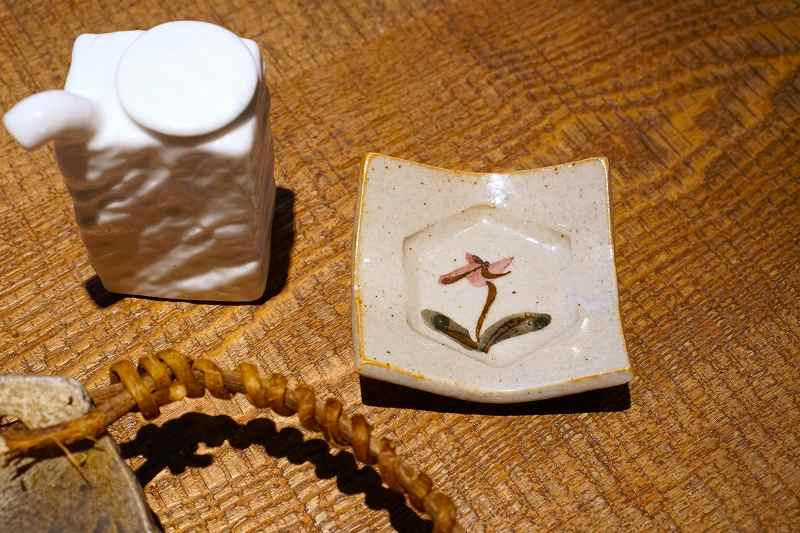 カタクリが描かれた千尋窯の醬油皿と醤油さしがテーブルに置かれている