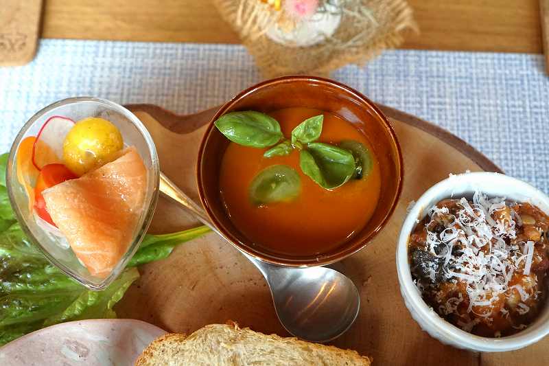 木のトレイにのせられた「サーモンのカルパッチョ」「トマトの冷製スープ」「ラタトゥイユ」がテーブルに置かれている