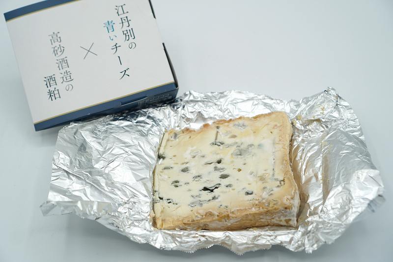 包みをあけたブルーチーズ「旭川 - 江丹別の青いチーズ  酒粕熟成 -」がテーブルに置かれている