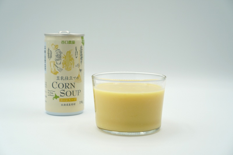コップに入れられた旭川の谷口農場の「豆乳仕立てのコーンスープ」がテーブルに置かれている