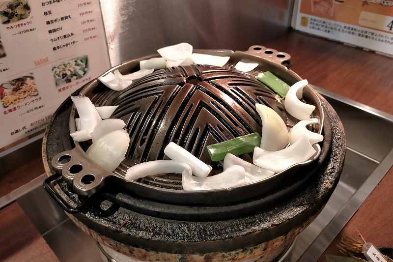 夜空のジンギスカンの鍋の上で野菜が焼かれている