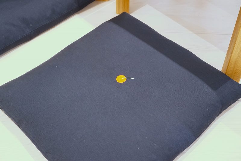 佐藤のアイコン「さくらんぼ」があしらわれた座布団が床に置かれている