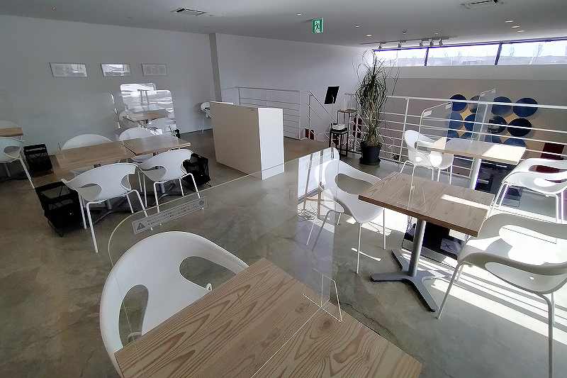 白い椅子と木のテーブルが並べられている「ノースファームストック ショップ&カフェ」の内観