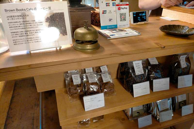 オーガニックコーヒー豆や焼き菓子が木の棚に置かれている、ブラウンブックスカフェの内観