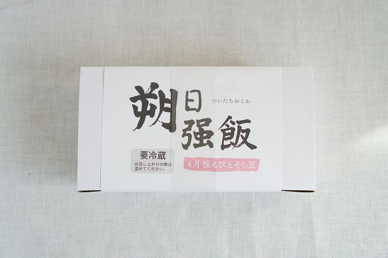 「六花亭 朔日おこわ」の2022年4月分 桜えびとそら豆おこわの箱がテーブルに置かれている