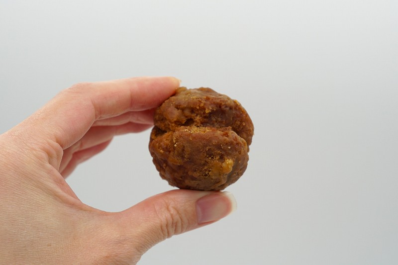 沖縄菓子処 琉宮 サーターアンダギーの黒糖ピーナッツ味を手に持っている様子