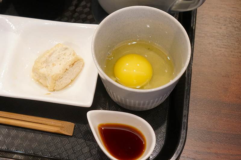 生卵が入った器と醤油がテーブルに置かれている