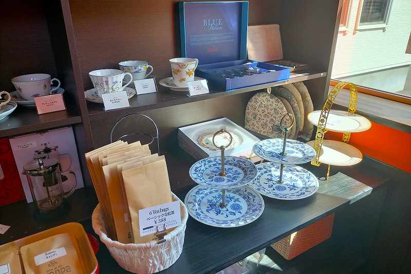 紅茶用のカップ＆ソーサーなどが木の棚に並べられている、グランパの内観