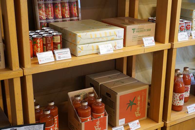 缶や瓶に入ったトマトジュースが木の棚に並べられている谷口農場直売所の内観