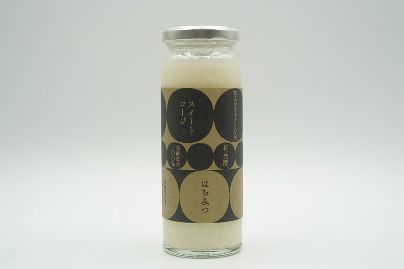 旭川山路養蜂場のはちみつを使用した「スイートコージ はちみつ」の瓶がテーブルに置かれている