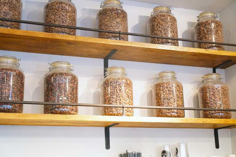 壁の棚にカカオ豆が入った大瓶が並べられたMinimal 富ヶ谷本店の内観