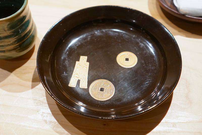 日本初の流通貨幣「和同開珎（わどうかいちん」をモチーフにしたプレートがテーブルに置かれている