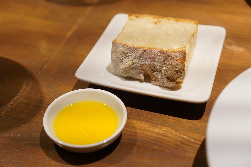 自家製パンと小さな皿に入れられたオリーブオイルがテーブルに置かれている