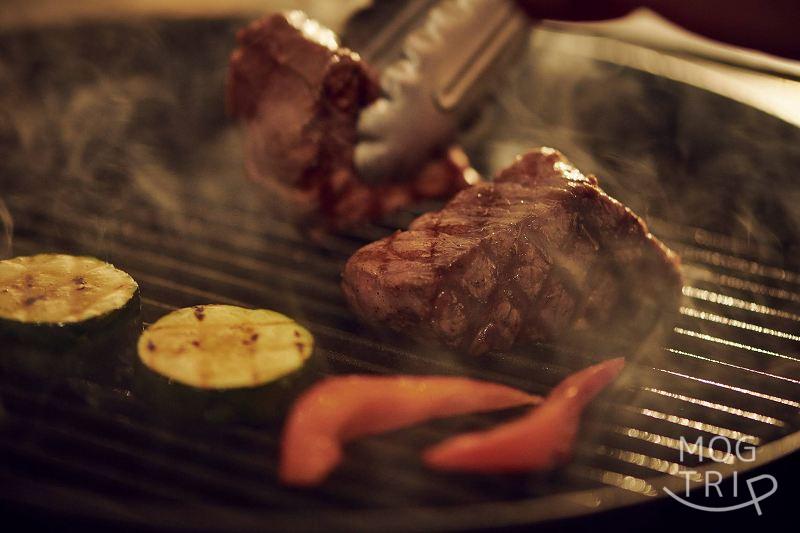 「THE GARDEN SAPPORO -HOKKAIDO GRILLE-（ザ ガーデン サッポロ 北海道グリル）」の肉が焼ける様子