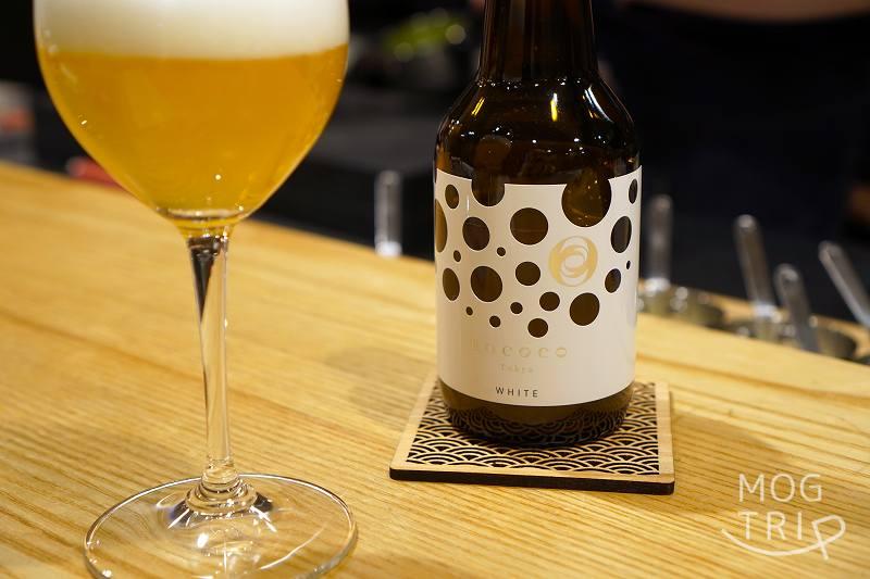 日本初の “ラグジュアリービール”「ROCOCO Tokyo」のボトルとグラスがテーブルに置かれている