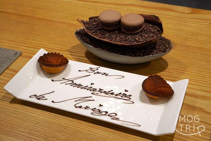 チョコレートマカロンと、メッセージプレートにのせられたハート型のマドレーヌがテーブルに置かれている