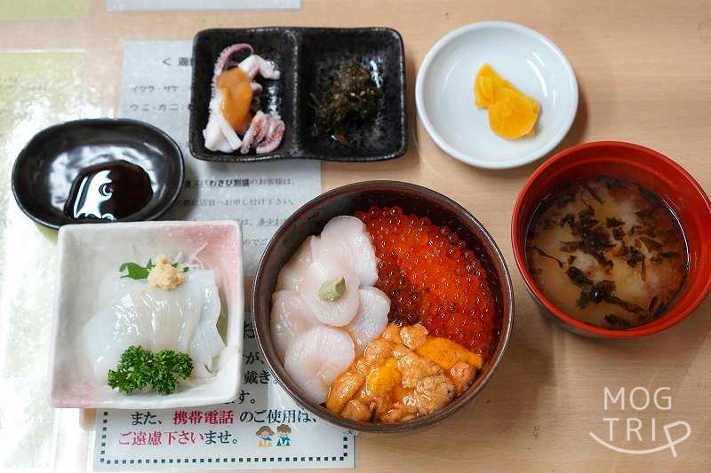 「きくよ食堂」の元祖函館巴丼・イカ刺しセットがテーブルに置かれている