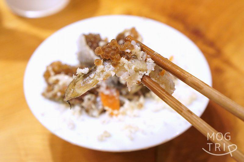子持ちハタハタの飯寿司を箸で持ち上げている様子