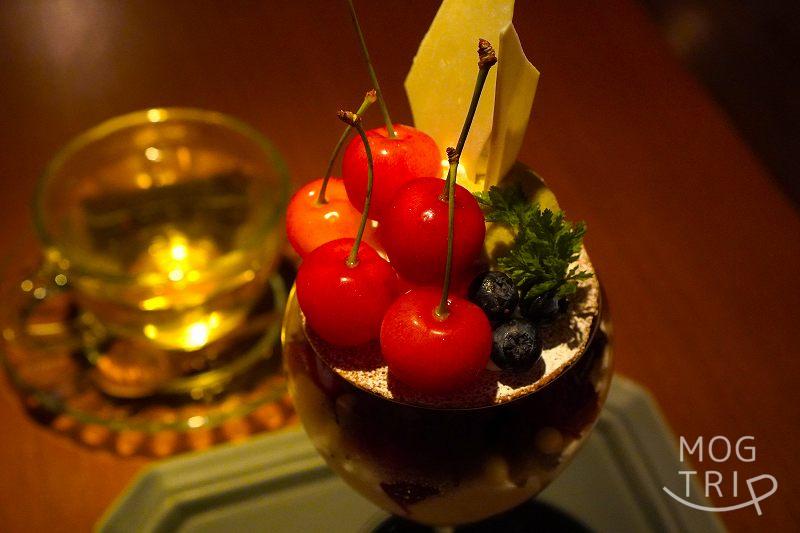 バーシェアーズ ヒシイの月替わりパフェ「さくらんぼと自家製ジェラートのパフェ」がテーブルに置かれている