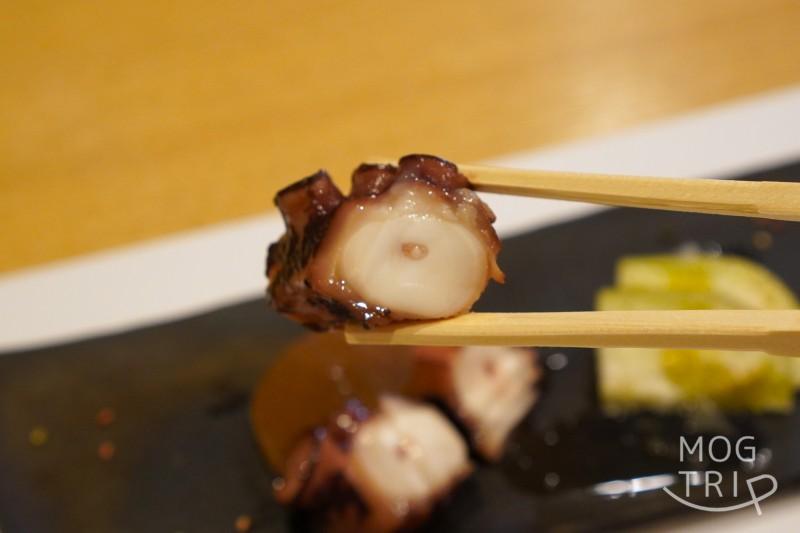 旭川「小西鮨」の煮ダコを箸で持ち上げている様子